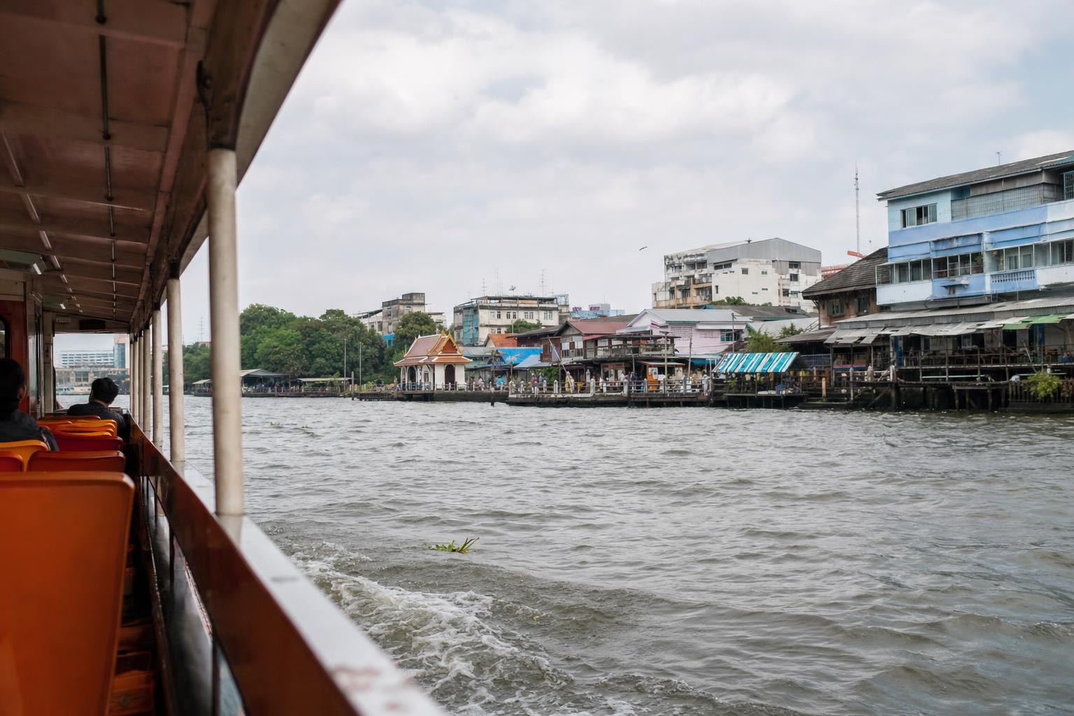 AI-generated illustration: View from an ordinary passenger river boat on the Chao Phraya River in Bangkok, Thailand, modest riverside buildings and water behind, candid daytime travel photography, no giant combined temples or palace skyline.